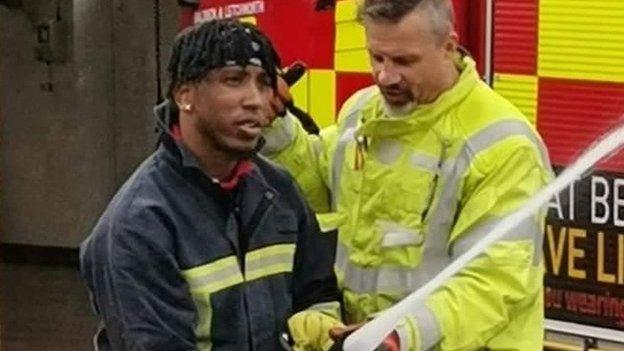 Kevon McPherson learns how to hold a fire hose with a trainer