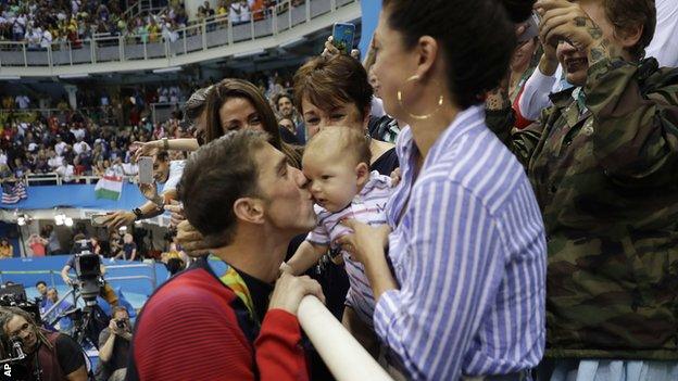 Michael Phelps gives his baby Boomer a kiss after getting his 200m butterfly gold