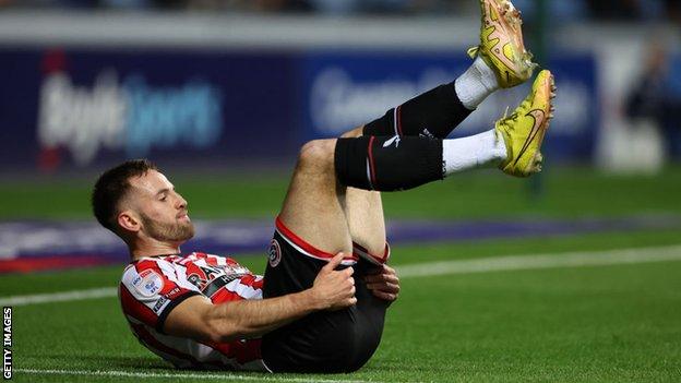 Rhys Norrington-Davies injured on the ground before he is stretchered off for Sheffield United at Coventry