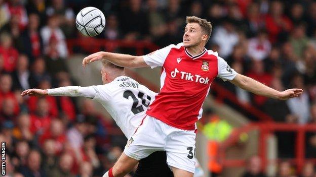 Stockport's Elliot Newby competes for the ball with Wrexham's James Jones.