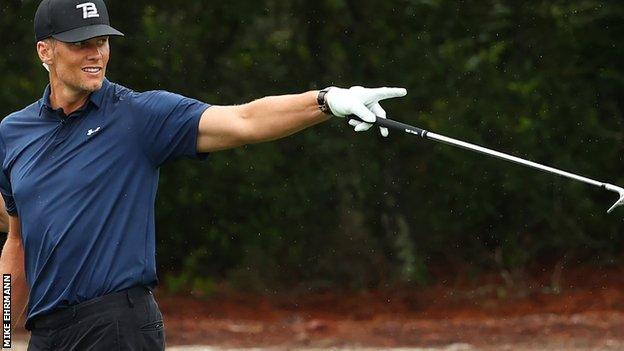 Tom Brady on golf-course, points to something