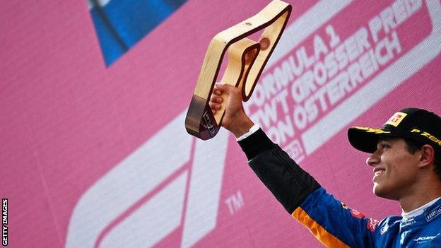 Lando Norris holds his third place trophy aloft