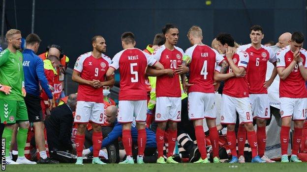 Denmark players form a ring around Christian Eriksen