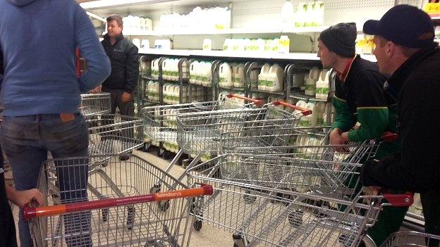 The farmers surrounded the milk fridge in an attempt to let shoppers know how their incomes have fallen.