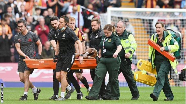 Emmanuel Osadebe is stretchered off for Bradford