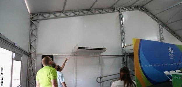 Staff look at a bullet hole inside the media centre at the Olympic Equestrian Centre