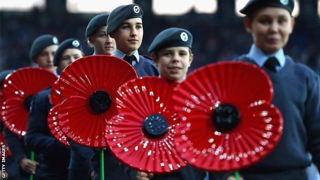 Military personnel carry giant poppies pitchside to mark Remembrance Day