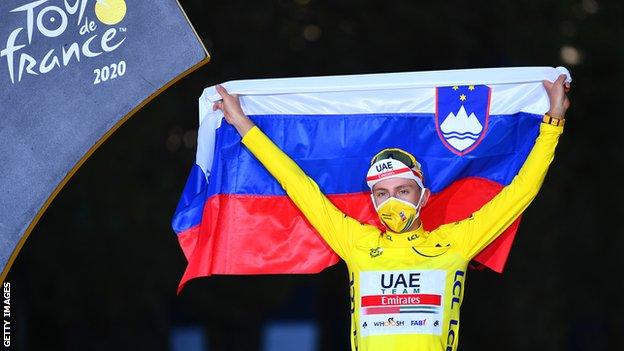 Tadej Pogacar holds up the Slovenian flag in celebration after winning the 2020 Tour de France