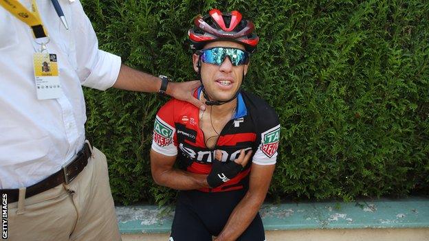 Richie Porte sits by the side of the road after suffering a suspected broken collar bone