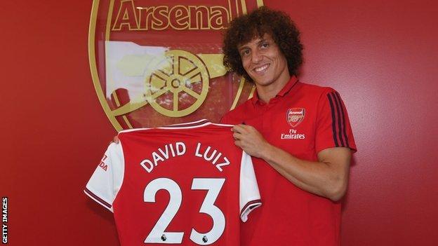 David Luiz holds an Arsenal shirt