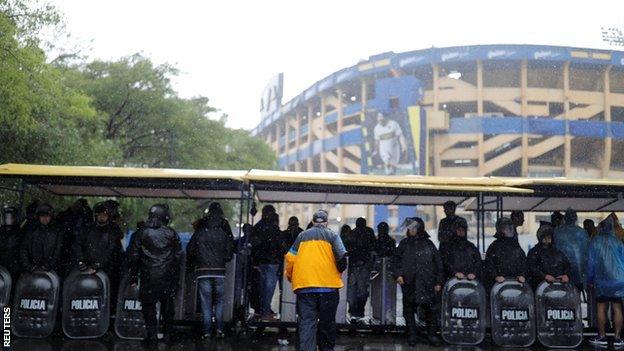 Riot police shelter from the rain outside Boca's La Bombonera stadium