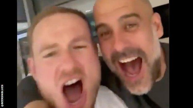 Pep Guardiola and a member of Manchester City staff sing.