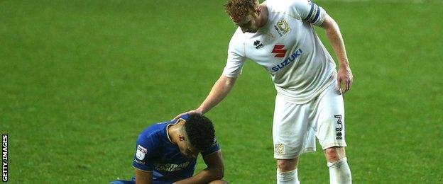 Dean Lewington of MK Dons (R) pats Lyle Taylor of AFC Wimbledon (L) after the final whistle