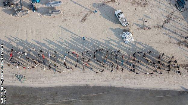 Sailors stand in formation to spell out #Sailors4TheSea