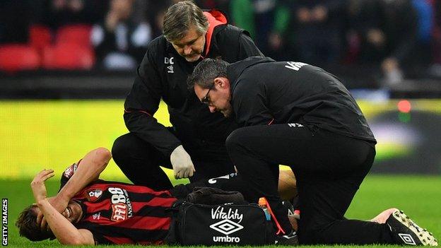 Bournemouth captain Simon Francis puts his hands over his head in agony as he receives medical treatment for a knee injury on the pitch against Tottenham