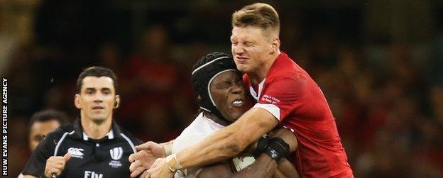 Wales fly-half Dan Biggar tackles England lock Maro Itojie