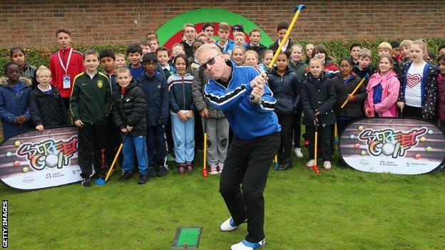 Keith Pelley, Chief Executive of The European Tour, plays a shot as he watched by members of the Golf Foundation's Street Golf