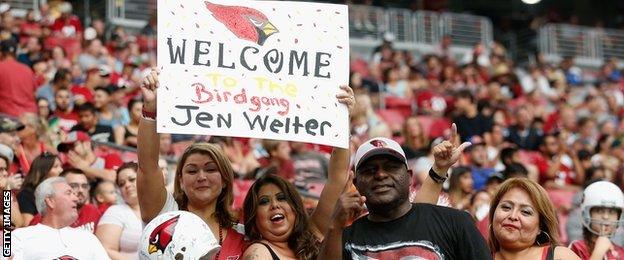 Fans of the Arizona Cardinals hold up a sign to welcome Jen Welter during team training