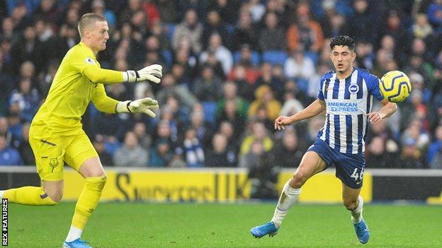 Steven Alzate challenges for a ball with Jordan Pickford