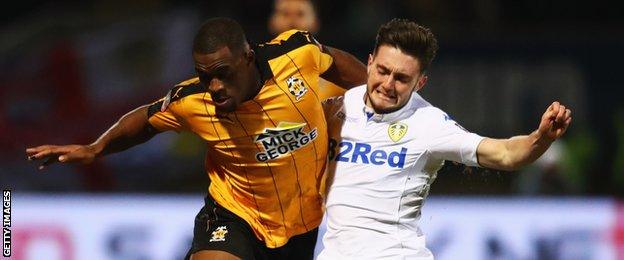 Matt Grimes playing for Leeds, challenging for possession by winning a header, in an FA Cup match against Cambridge United