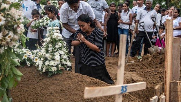 A woman grieves at the grave after a funeral for a person killed in the Easter Sunday attack on St Sebastian"s Church, on April 25, 2019