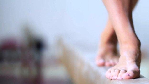 women's feet on a gymnastics beam