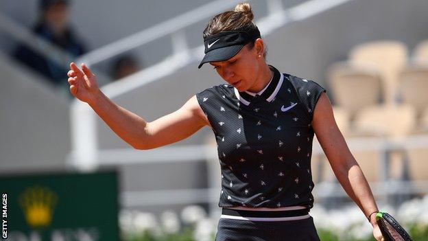 Halep holds up her hand and looks down in disappointment