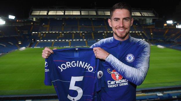 Jorginho holding a Chelsea shirt after signing for the Premier League club from Napoli