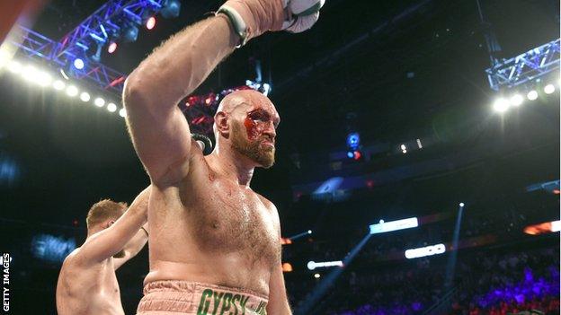 A bloodied Tyson Fury raises his glove at the end of the fight