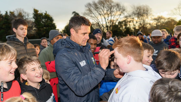 Dan Carter signs an autograph on a child's forehead