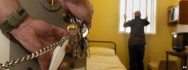 A prisoner in a cell and a guard with keys in the lock