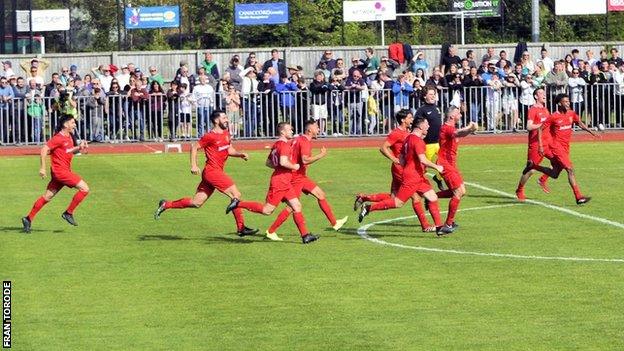 Jersey's players rush to congratulate Karl Hinds after he scored the winning penalty