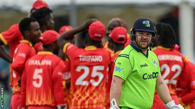 A dejected Paul Stirling walks off as Zimbabwe celebrate dismissing the Irish opener