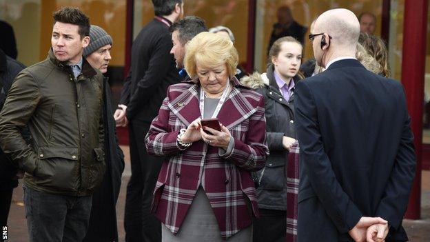 Anne Budge looks at her phone after waiting outside Tynecastle after a fire alarm caused an evacuation