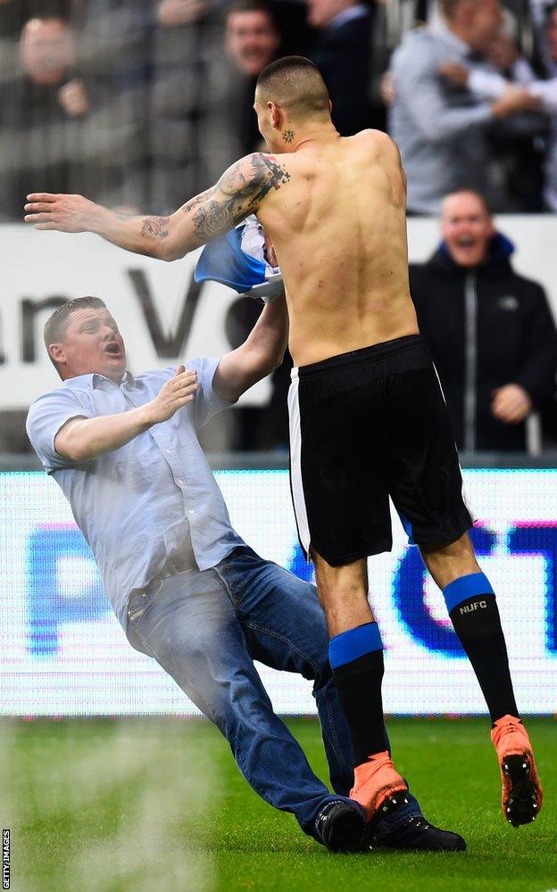 Aleksandar Mitrovic celebrates as a fan slips in front of him