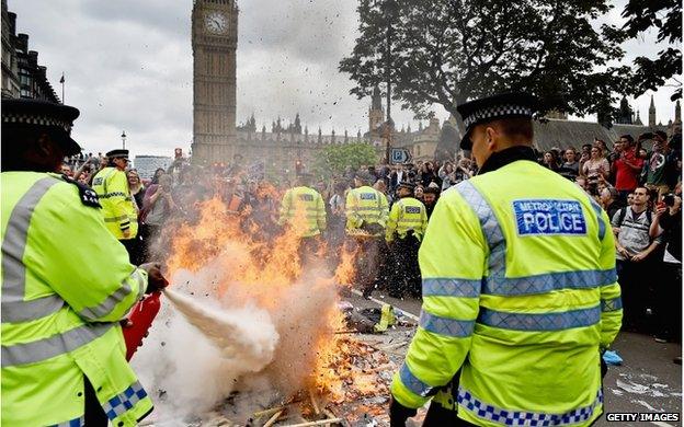 Police officers putting out a fire made of protest placards near Parliament