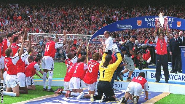 Robert Pires of Arsenal lifts the Premier League Trophy as his team mates kneel before him, May 2002