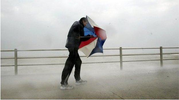 A man holding an umbrella in windy weather