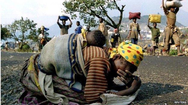 A Rwandan woman collapses with her baby on her back alongside the road connecting Kibumba refugee camp in 1994