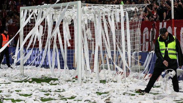 Security staff clear toilet roll from the pitch before the second half of Mainz against Freiburg