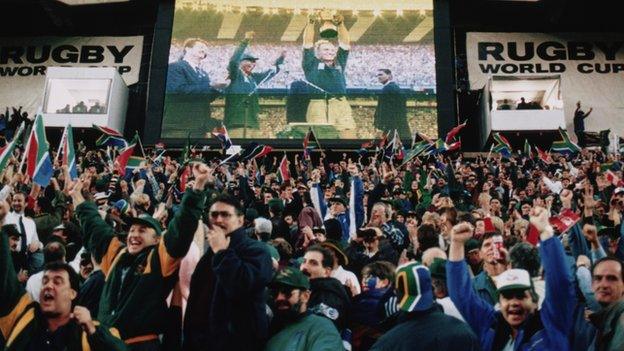 South African fans watch Francois Pienaar lift the trophy after South Africa defeated New Zealand in the Rugby World Cup final at Ellis Park, Johannesburg, 24th June 1995