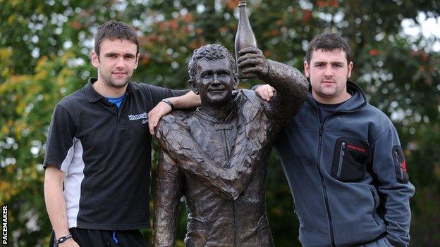 William Dunlop and brother Michael with a statue erected in Ballymoney in memory of their father Robert