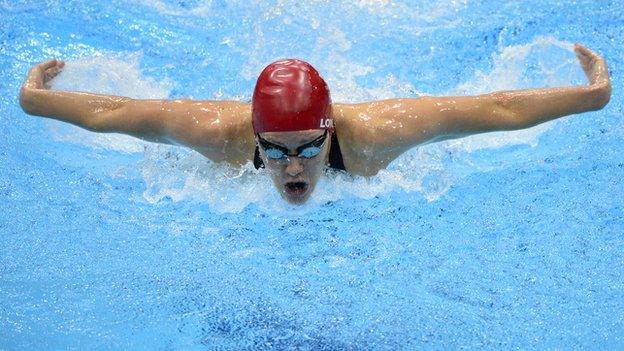 Jemma Lowe swimming towards the camera in a red swim cap