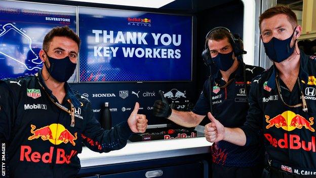 Red Bull personnel wearing face masks and giving a thumbs up in front of a screen that says 'Thank you key workers'