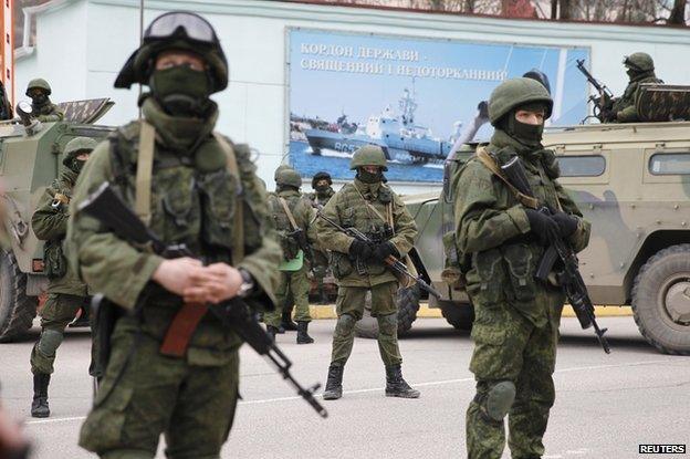 Armed servicemen wait near Russian army vehicles outside a Ukrainian border guard post in the Crimean town of Balaclava, March 1, 2014.