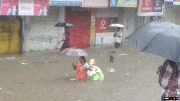 Mumbai residents brave the rain, walking past closed shops on flooded streets