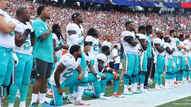 Miami Dolphin players kneel during the US national anthem