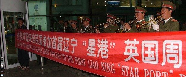 Stockport players greeted at airport by military band