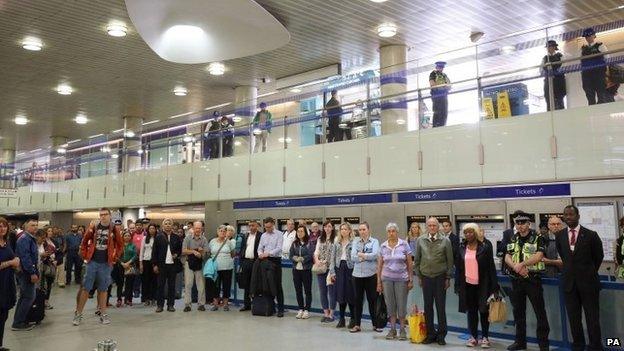 People pause for a minute's silence at King's Cross Underground station in London