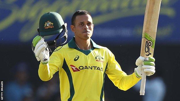 Australia opener Usman Khawaja takes off his helmet and raises his bat to celebrate his maiden ODI century